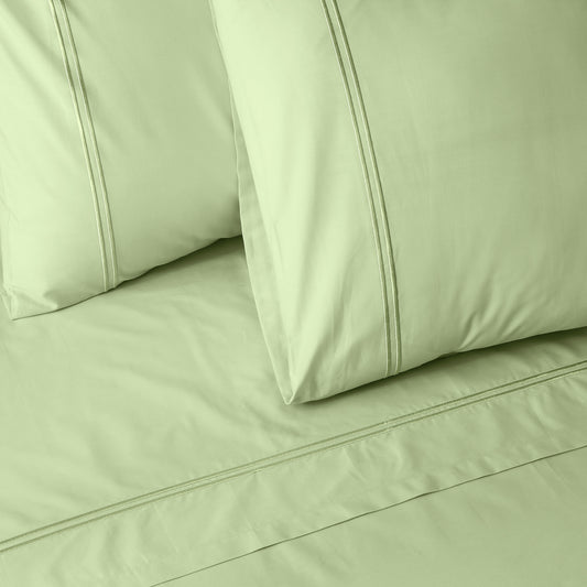 Close-up of light green colour luxury embroidered bedding with two pillows on a matching bed sheet.