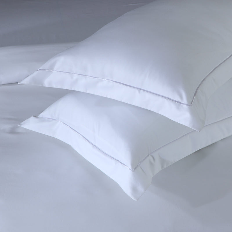 Organic cotton oxford pillowcases stacked elegantly on a soft bed sheet, showcasing luxury and comfort.