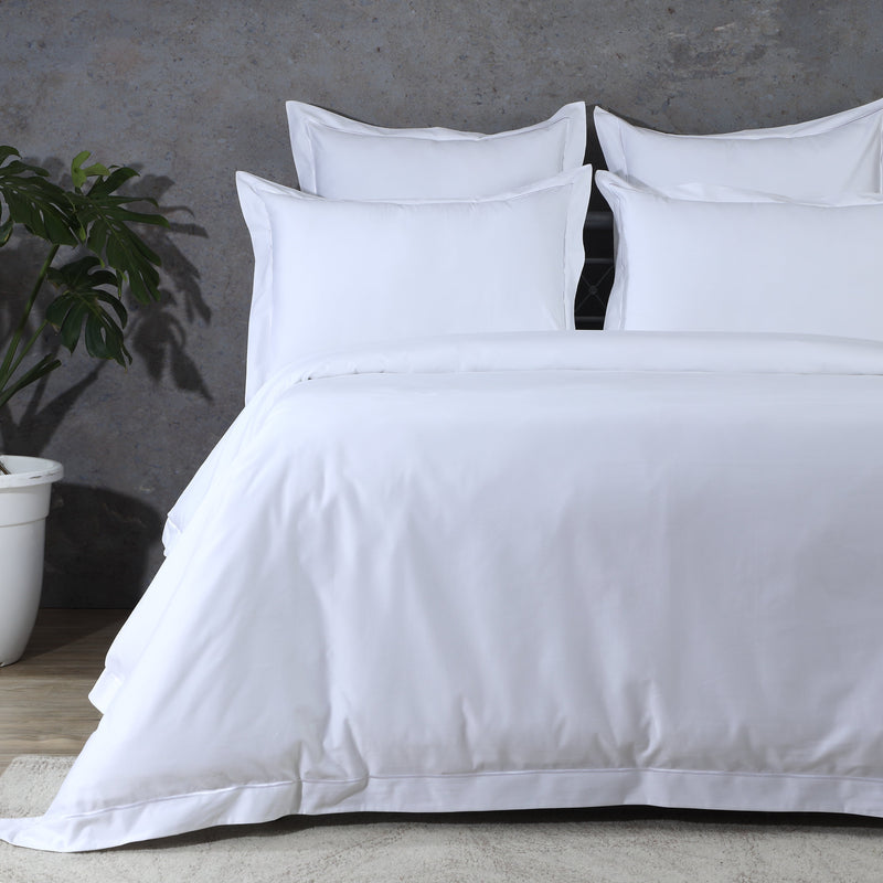 1000 TC organic cotton duvet cover sets displayed on a bed with white pillows and a green plant.