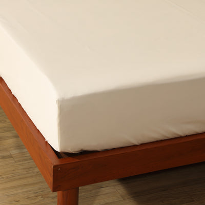 Ivory 600TC organic cotton fitted sheet on a styled bed – warm ivory tone with silky 600 thread count weave, deep 35cm elasticated drop, Whites of London India