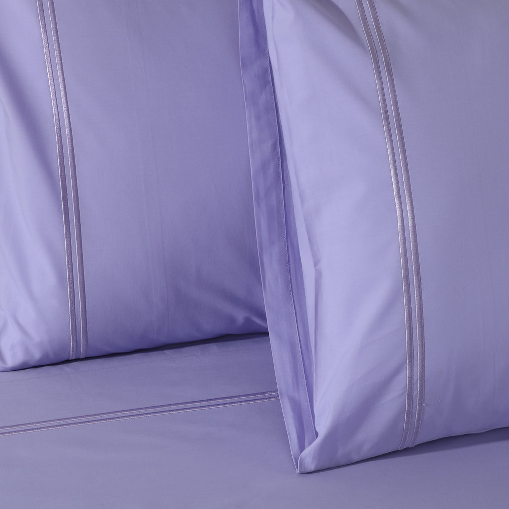 Close-up of Lavender Mist organic cotton percale pillowcase embroidery – understated stitching on a soft pastel lavender 200TC dyed sheet set, Whites of London India