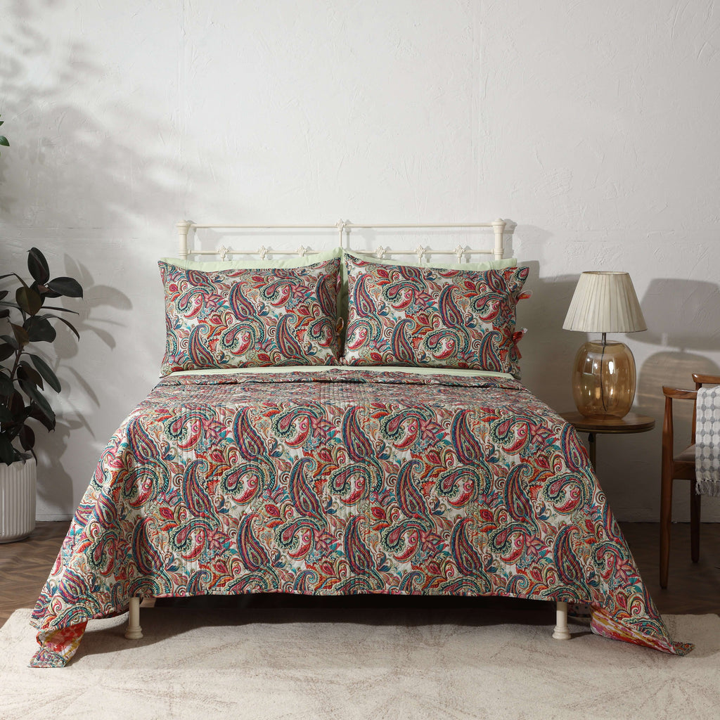 Paisley Romance reversible dohar set on a styled bed – vibrant paisley print in teal, coral, rose and gold on ivory organic cotton percale, Whites of London