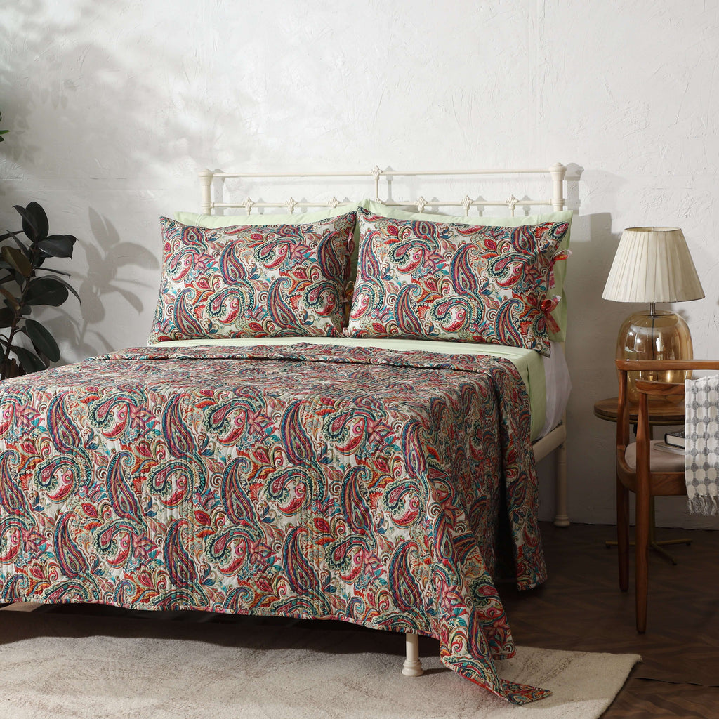 Paisley Romance quilted dohar set on a made bed – side angle view with paisley motifs in rich teal and coral tones