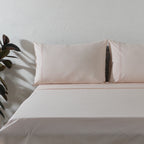 Peach Mist dyed organic cotton sheet set on a styled bed – soft pastel peach flat sheet and pillowcases with minimalistic embroidery, 200 TC, Whites of London India