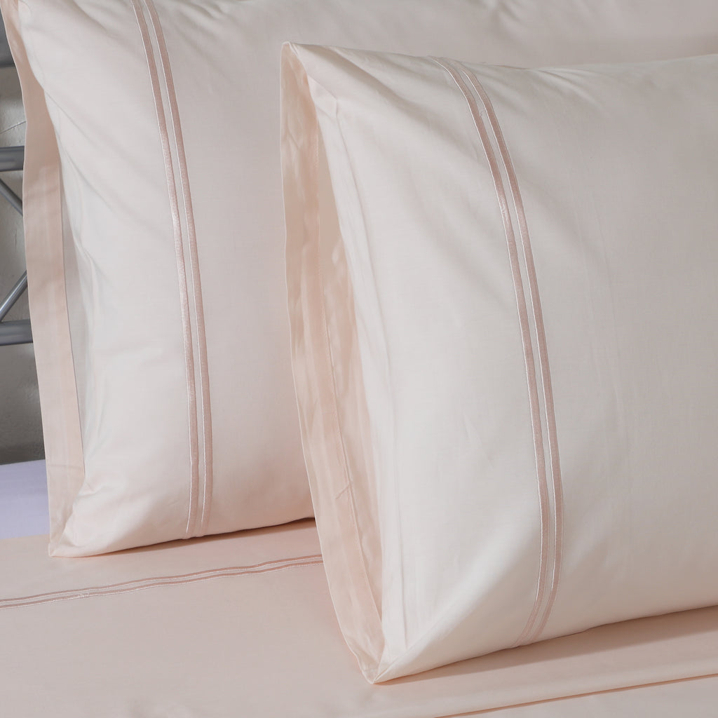 Close-up of Peach Mist organic cotton pillowcase embroidery – subtle, understated stitching on a soft pastel peach 200TC dyed cotton flat sheet set, Whites of London India