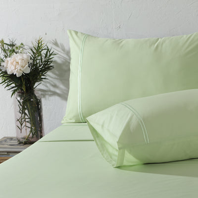 Reef dyed organic cotton sheet set on a styled bed – aqua-toned flat sheet and pillowcases with minimalistic embroidery, 200 TC organic cotton percale, Whites of London India