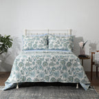 Cotton percale reversible dohar set in Jacobean Windflower on a made bed – soft ivory with blush-coral and slate-blue botanical print, lightly quilted for warmth