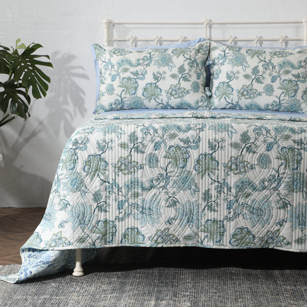 Jacobean Windflower cotton percale reversible dohar set on a styled bed – ivory ground with blush-coral botanical blooms and slate-blue vines, wave-quilted, Whites of London