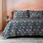 Quilted Chintz dohar draped on a bed – rich deep blue base with delicate floral and vine print, reversible organic cotton percale, Whites of London India