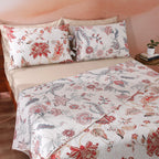 Ivory side of the Jacobean Summer percale dohar on a bed – soft blush-coral and slate-blue cotton percale botanical print, reversible with wave-quilted texture