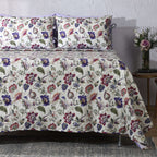 Lavender Fields reversible dohar set styled on a bed – floral print in lavender, violet and blush on ivory organic cotton percale, Whites of London