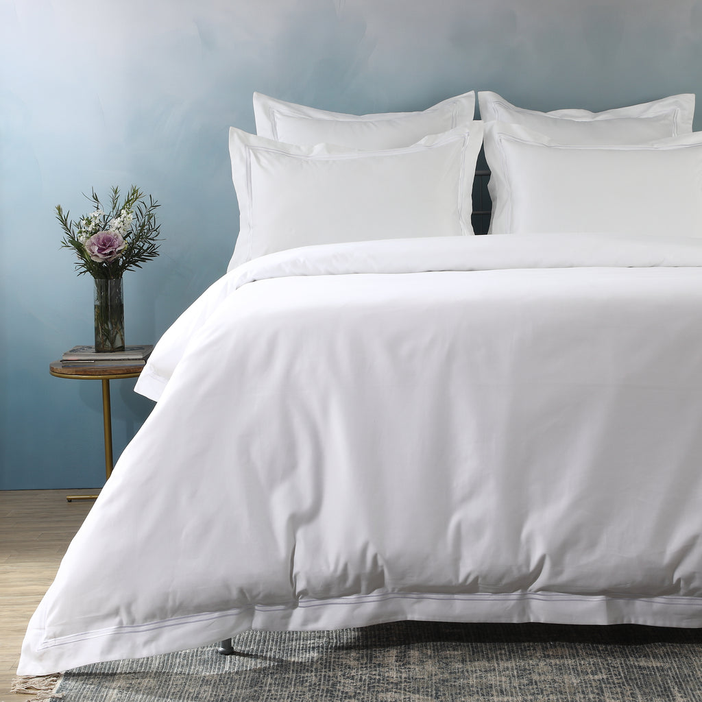 1000 thread count white organic cotton duvet cover and Oxford pillowcase set on a made bed – refined embroidery detailing and hidden button closure