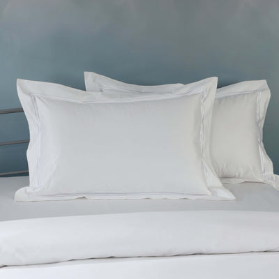 White organic cotton embroidered pillowcase set on a styled bed – 1000 TC organic cotton with double embroidered border detail, Whites of London