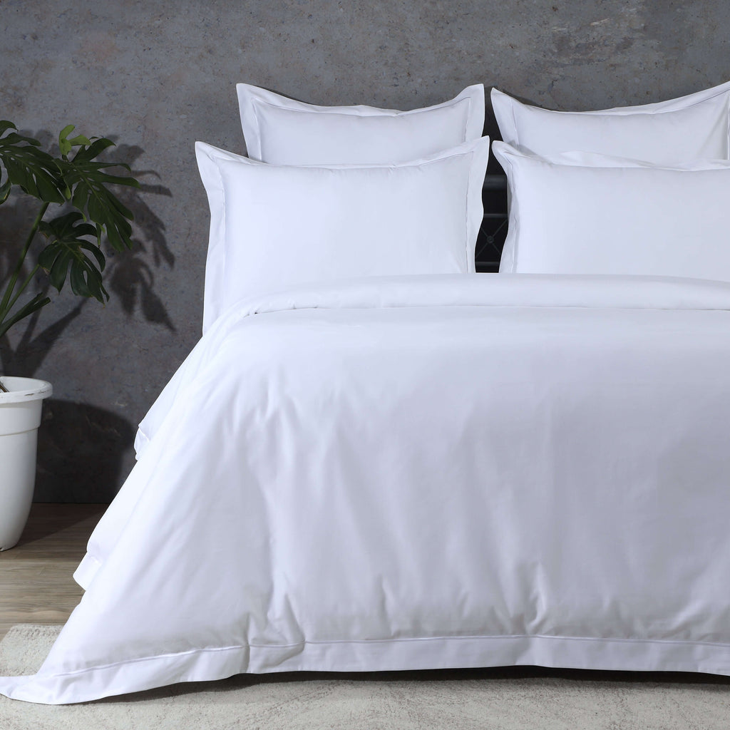 Pair of white 600 thread count organic cotton euro pillowcases on a made bed – single-line embroidery on face and flange, 65x65cm