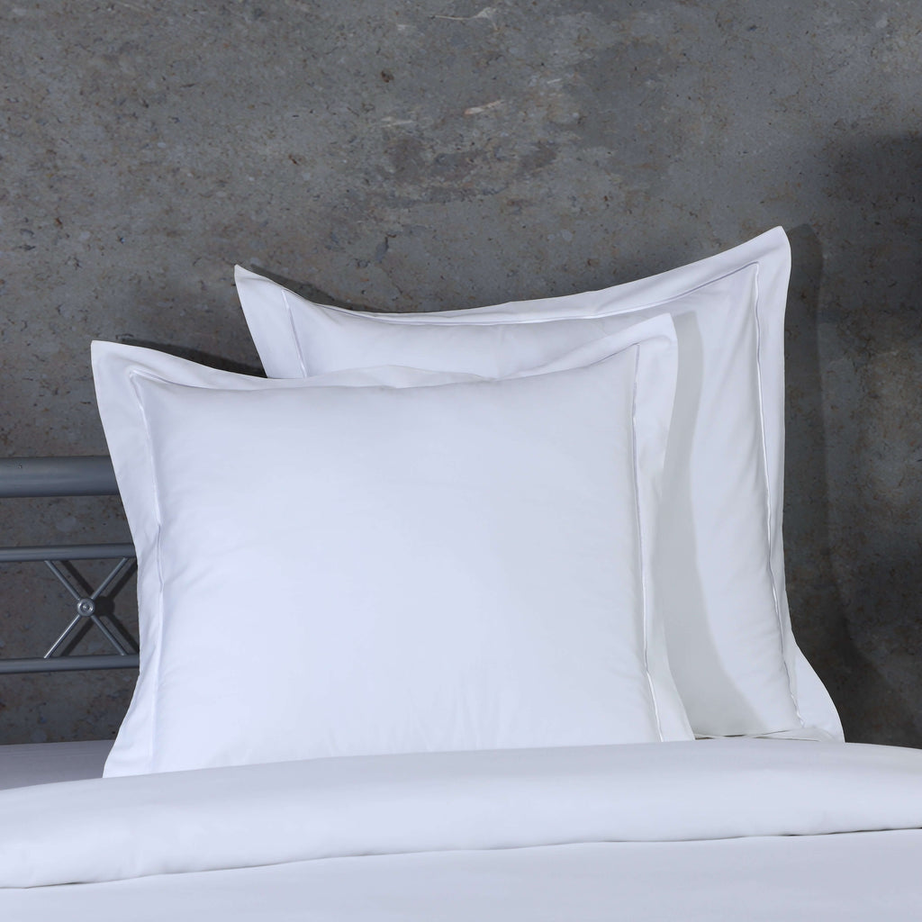 White euro pillowcase set styled on a bed against a rustic background – 600 TC organic cotton with single embroidered border, Whites of London India