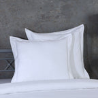 White euro pillowcase set styled on a bed against a rustic background – 600 TC organic cotton with single embroidered border, Whites of London India