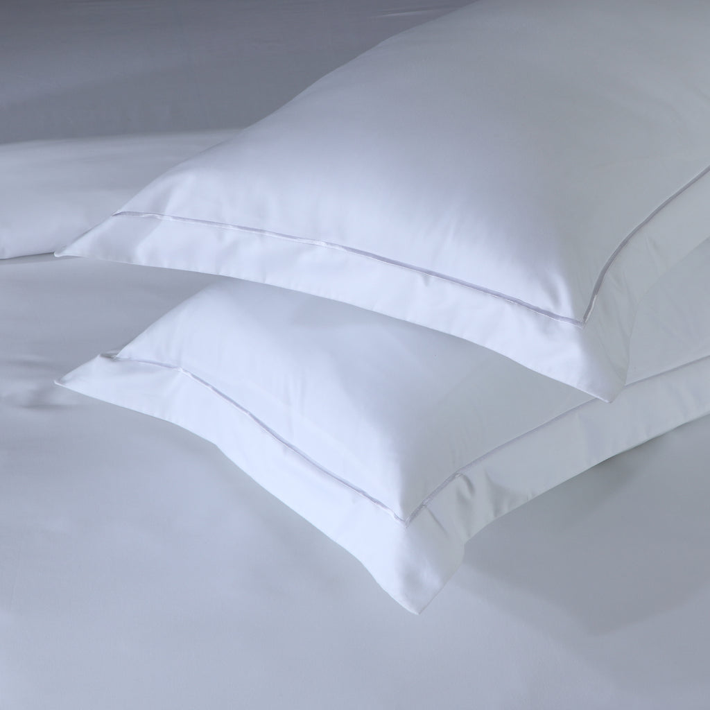 Close-up of single embroidery line on a white 600 TC organic cotton oxford pillowcase – dense, silky weave with refined flange detail