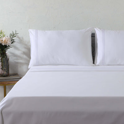 1000 TC white organic cotton embroidered sheet set on a luxury styled bed – silky flat sheet with three embroidery line and matching pillowcases, Whites of London